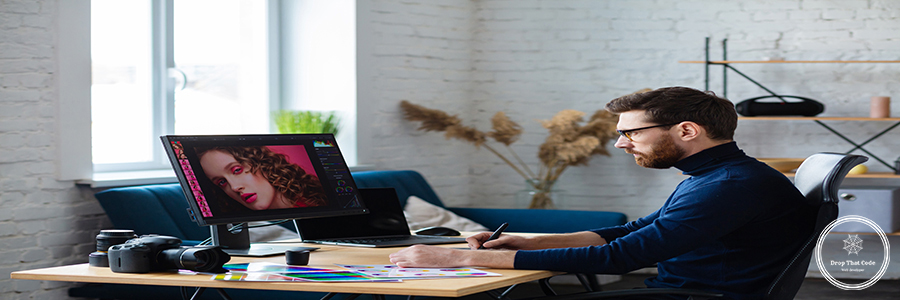 Retouching images in special program.Portrait of graphic designer working in office with laptop,monitor,graphic drawing tablet and color palette.Retoucher workplace in photo studio.Creative agency Retouching images in special program.Portrait of graphic designer working in office with laptop,monitor,graphic drawing tablet and color palette.Retoucher workplace in photo studio.Creative agency.