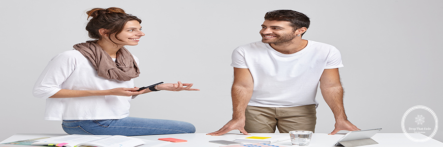 Two man and woman collegaues or partners have active discussion of future plans, look happily at each other. Stylish young female designer sits at desk, explains new strategy to unshaven male worker Two man and woman collegaues or partners have active discussion of future plans, look happily at each other. Stylish young female designer sits at desk, explains new strategy to unshaven male worker
