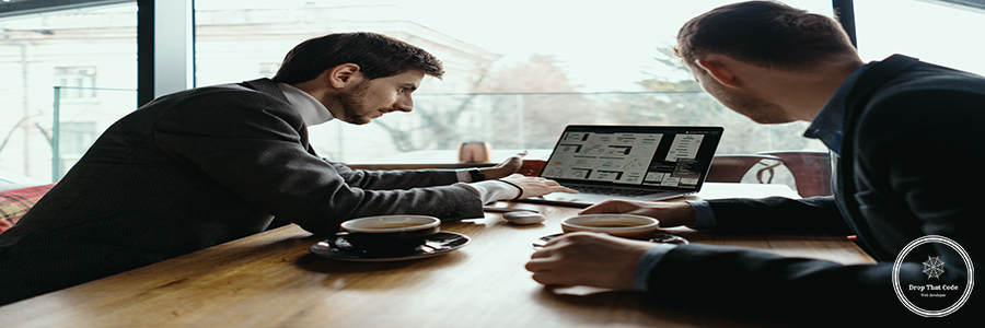 Two young businessman having a successful meeting at restaurant. Two businessmen talking about new opportunities sitting with laptop at desk, planning project, considering business offer, sharing ideas while drinking coffee together